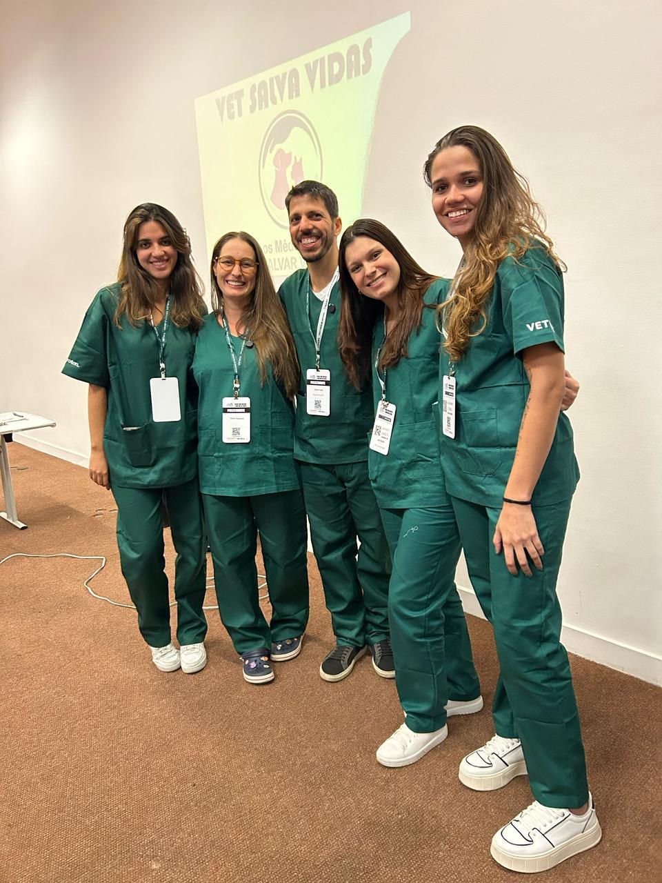 Equipe PenaVet de scrub verde na sala do workshop