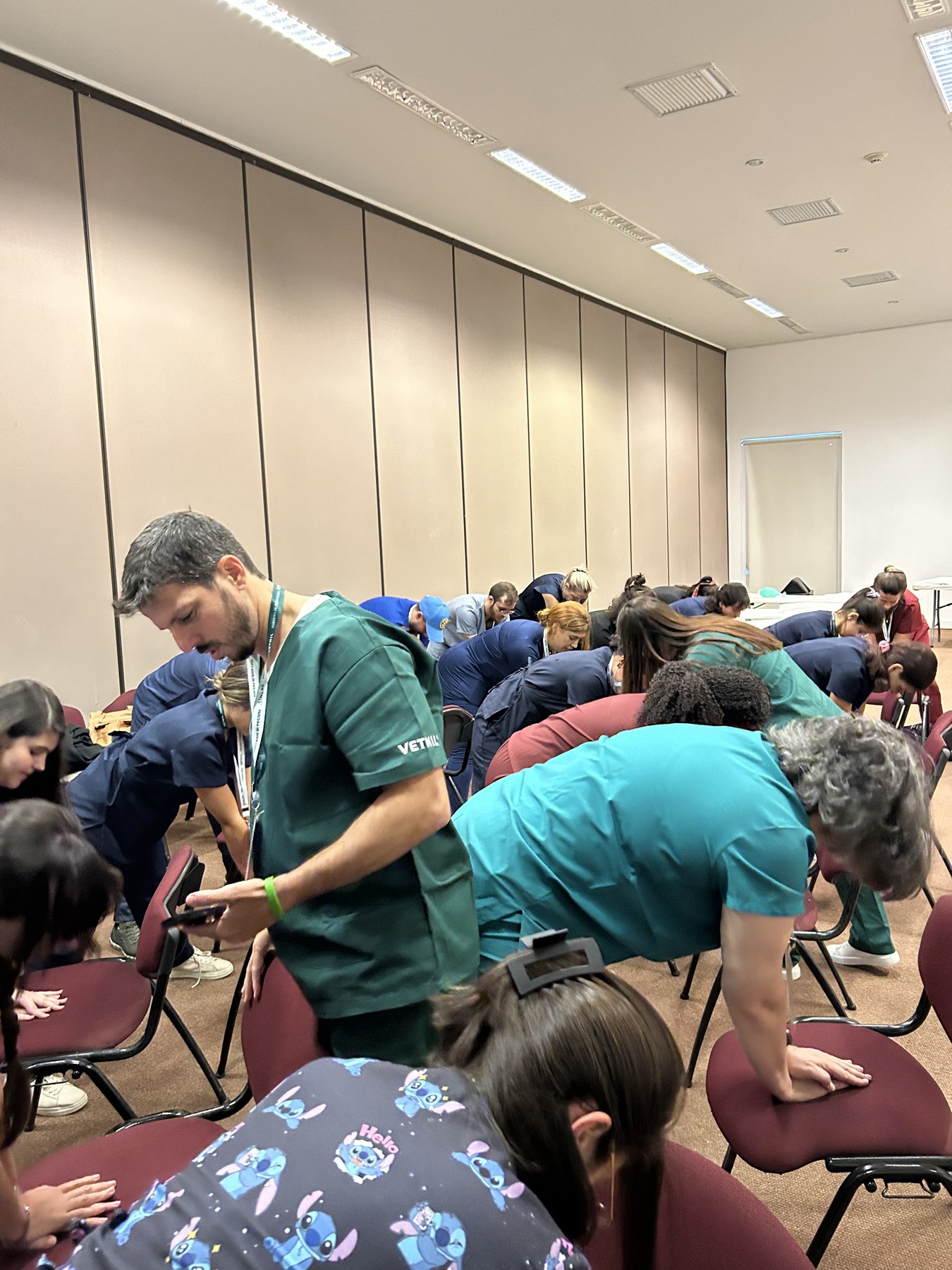 Sala inteira treinando massagem cardíaca, com a equipe supervisionando